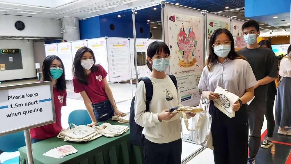 Students taking photos with Caring Leaders and Mindful Self-Compassion tote bags.